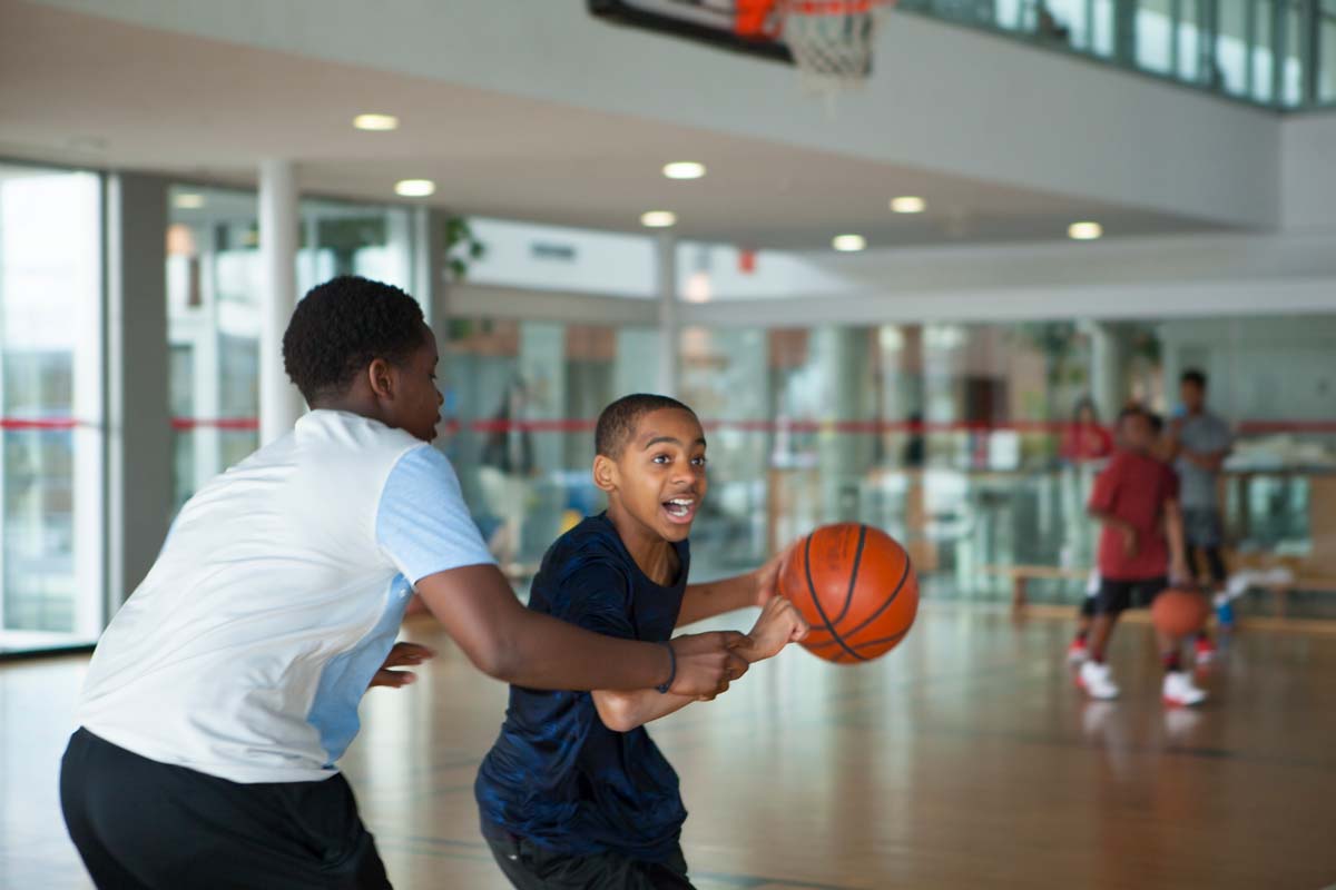 Two children playing basketball in the YMCA gym