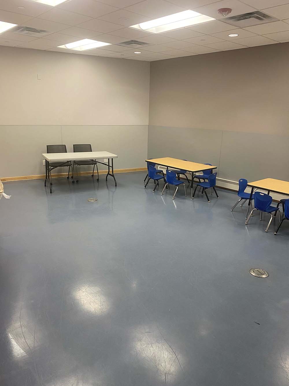 A room with three tables with chairs and a blue floor is shown