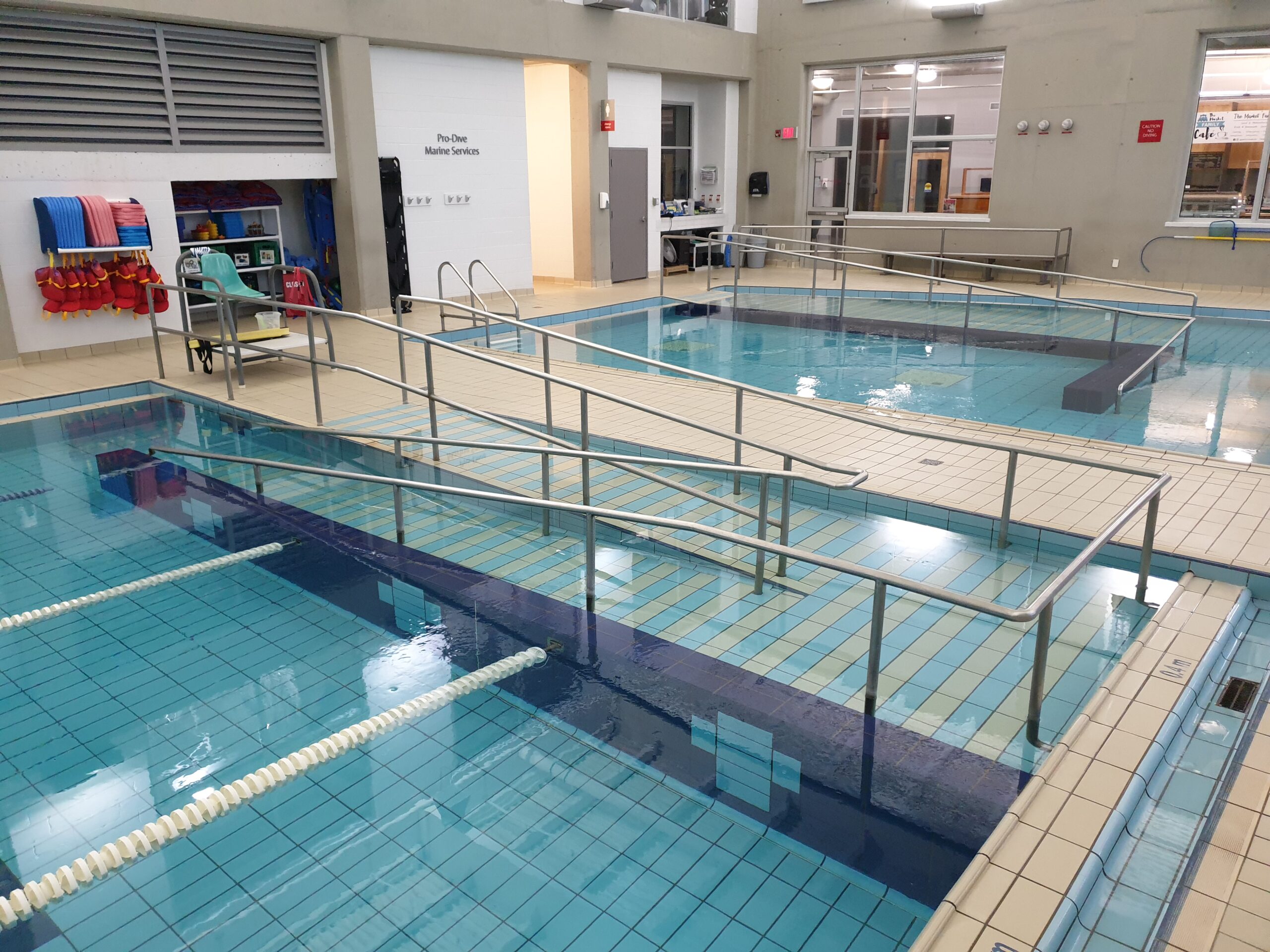 a wide angle view of a pool deck that has two pools with ramps