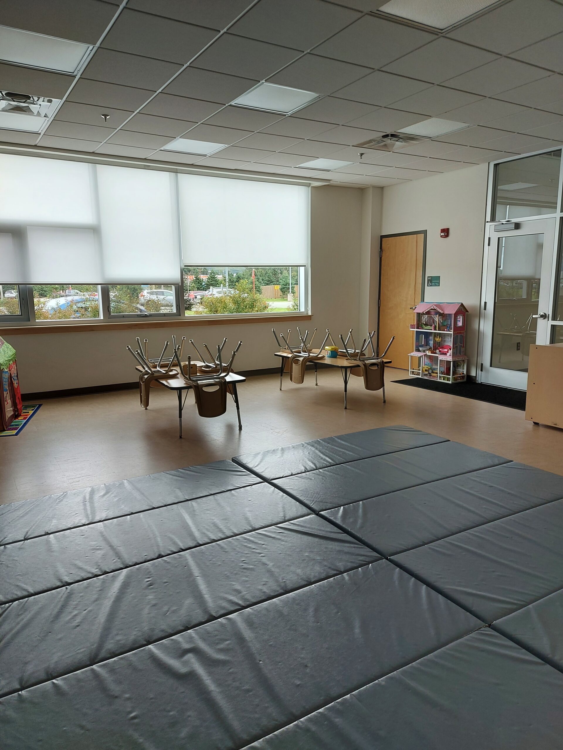 a rental room with mats on the floor, as well as children's tables and chairs, and toys