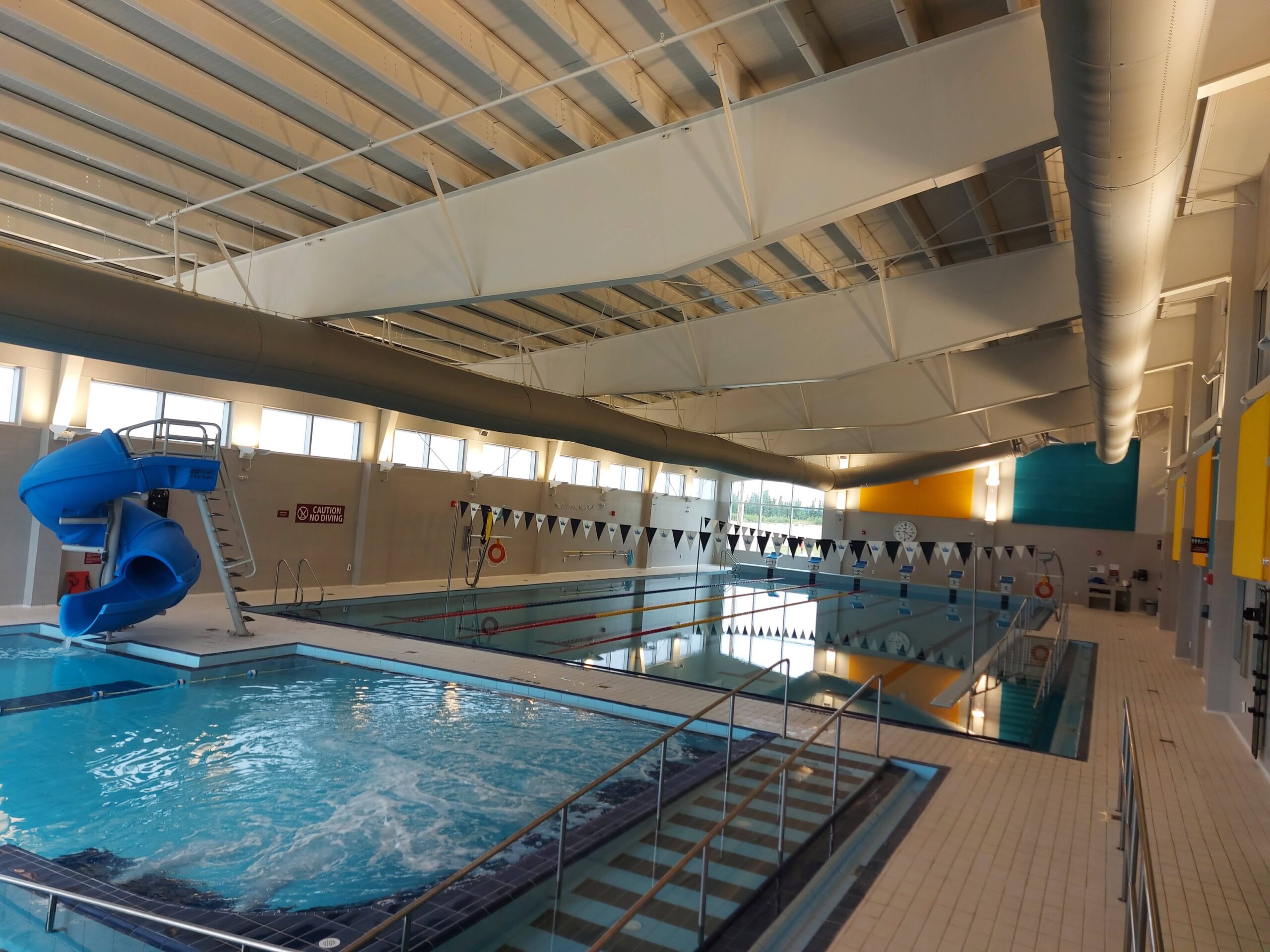 a high-up angle of two swimming pools, one with a water slide