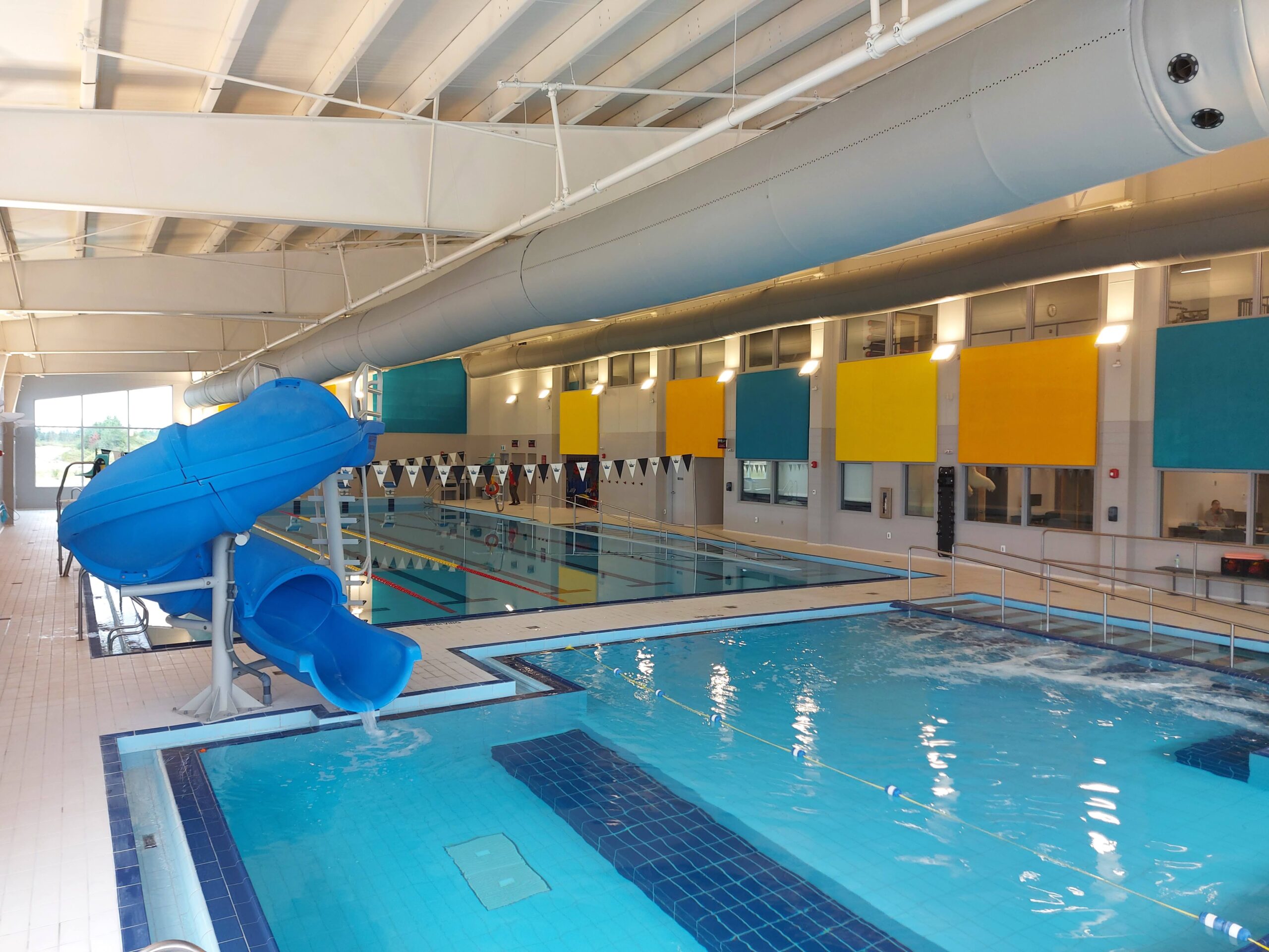 a high-up angle of two swimming pools, one with a water slide