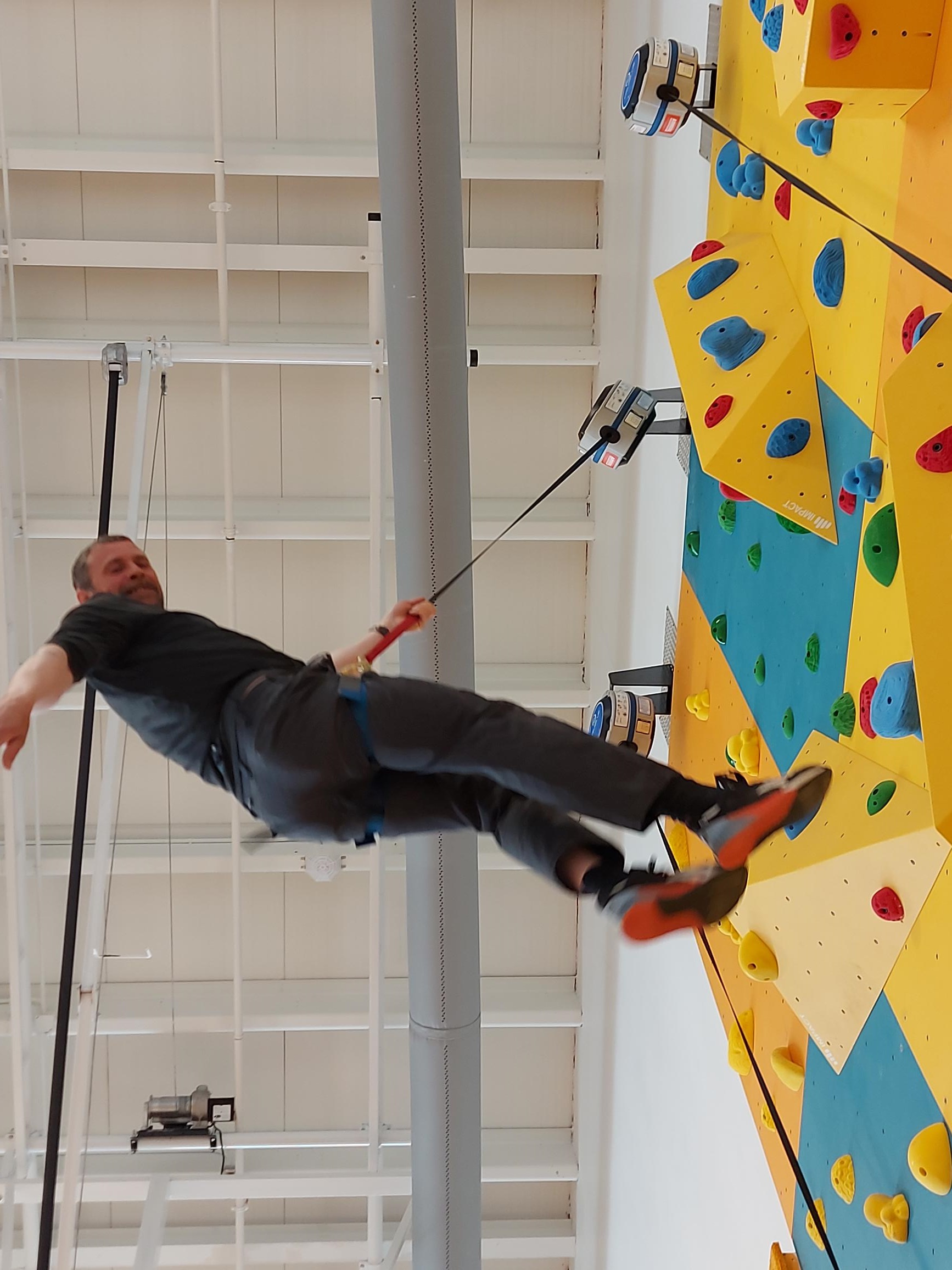 A man descending from the top of a rick climbing wall