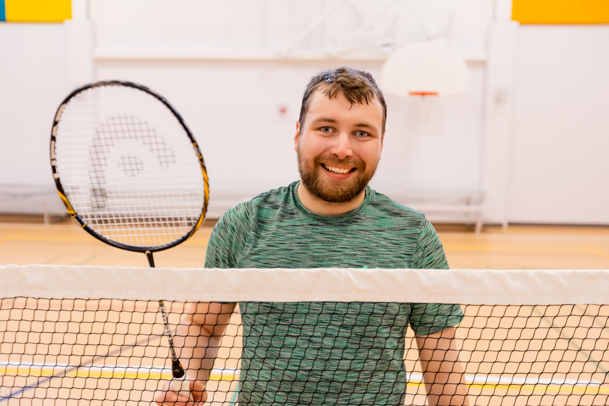 a man smiling holding a badminton racket