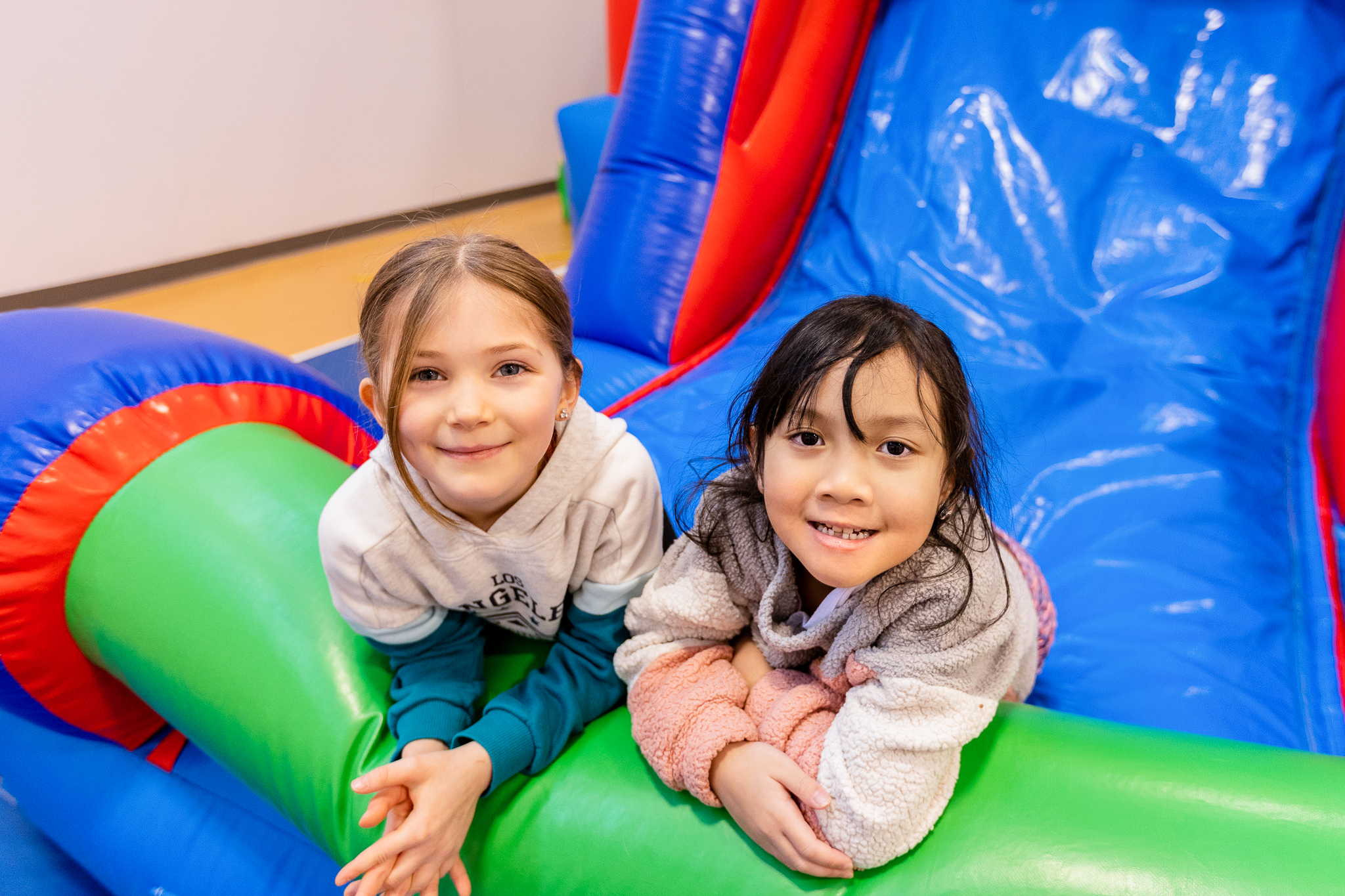 two young girls smile for a photo on a bouncy house