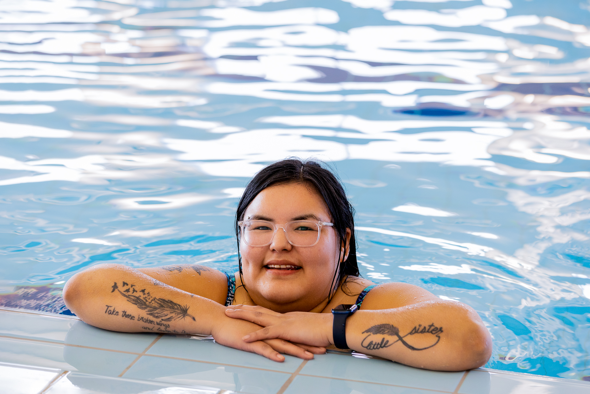 a woman leaning on the side of a pool smiling